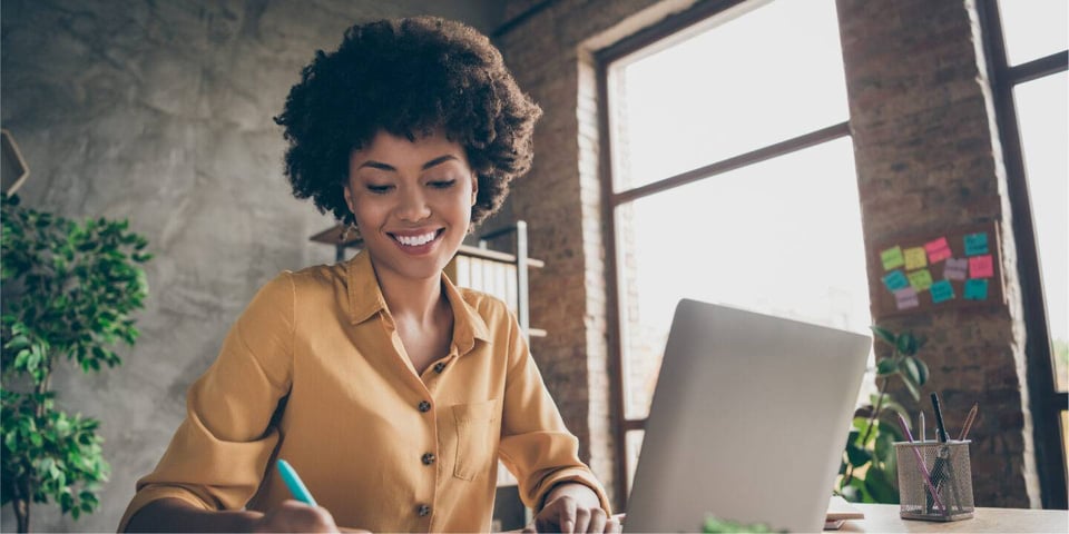 Woman using laptop and making notes