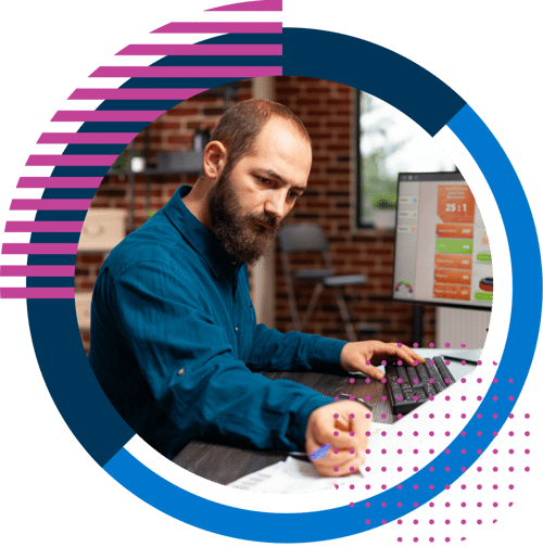 Man at desk using computer and writing notes