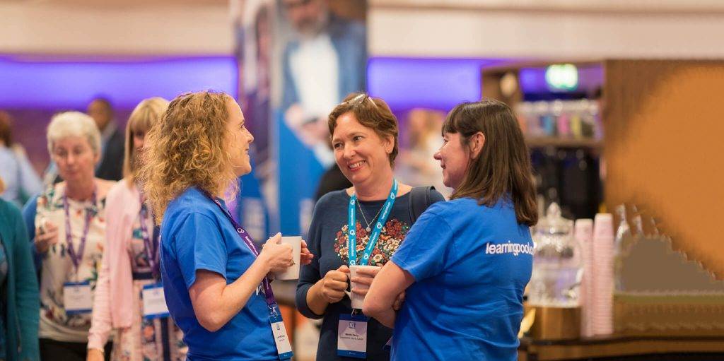 Two Learning Pool staff chatting to a customer at an internal event